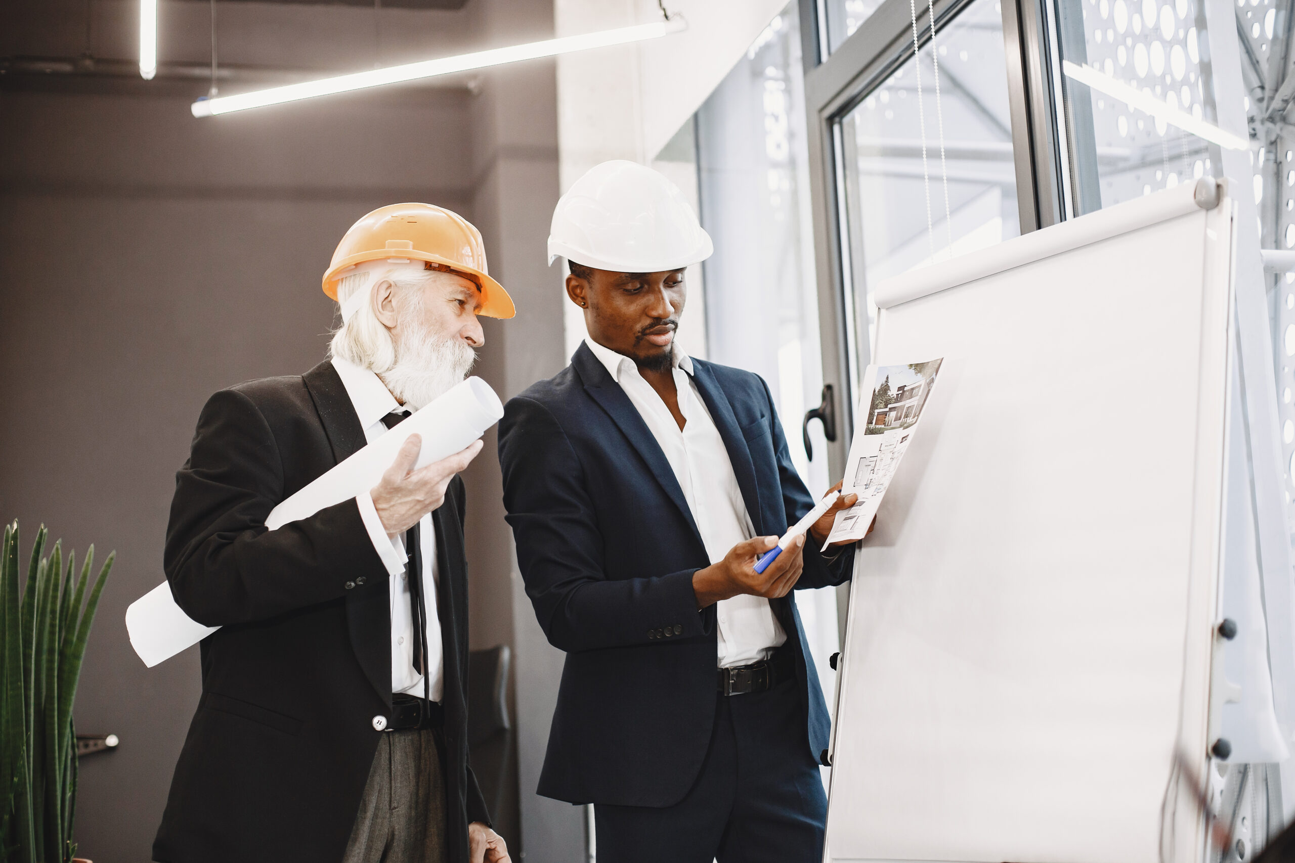 african man black suit old engineer with boss young guy with senior man writing board scaled